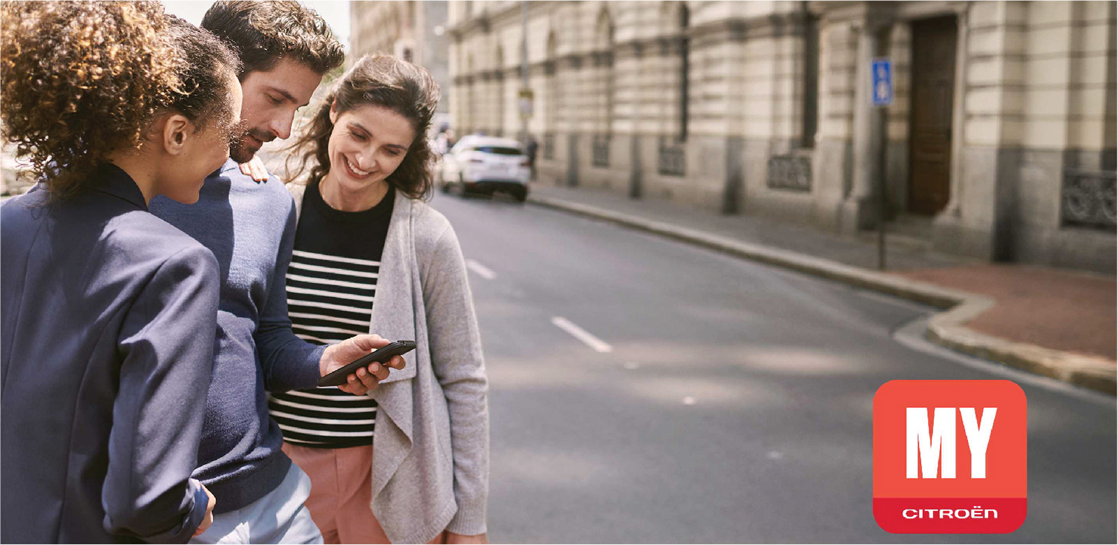 3 friends looking at a smartphone in the street